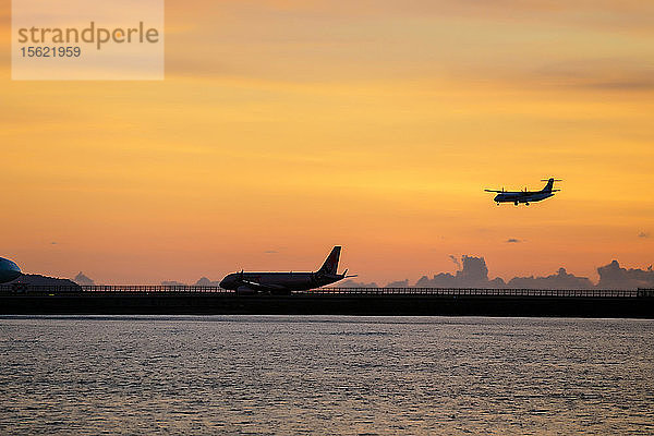 Silhouetten eines Flugzeugs auf der Startbahn und einer weiteren Landung