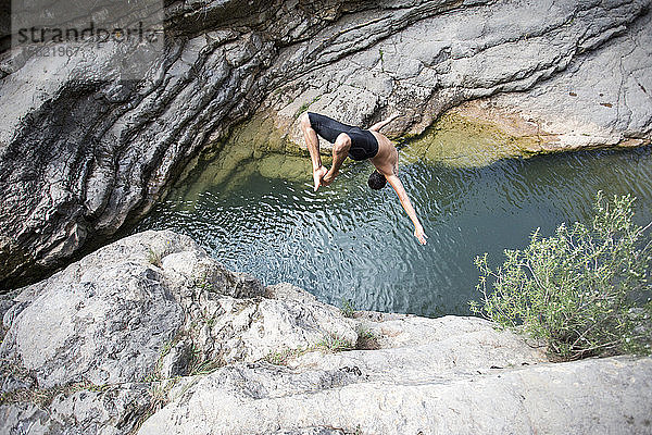 Ein junger Mann macht einen Rückwärtssalto in einen natürlichen Pool in Montanejos (Spanien).