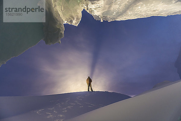 Ein Mann steht während eines Winterbesuchs in der Antarktis am Eingang einer Eishöhle.
