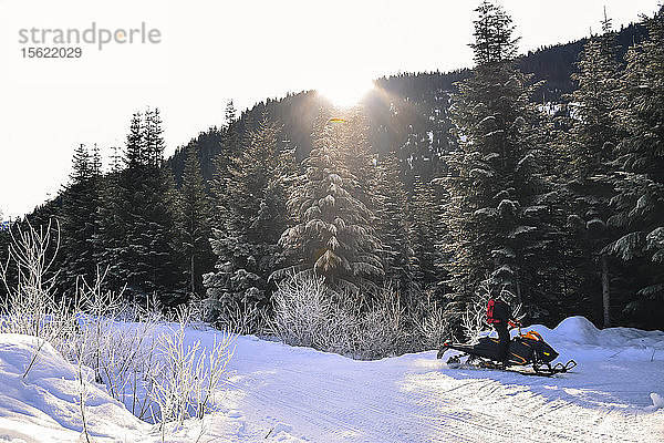 Entfernte Ansicht eines Mannes mit Schneemobil in der Nähe des Waldes  Callaghan Valley  Whistler  British Columbia  Kanada