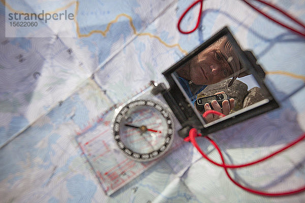 Person  die ein GPS hält  das sich im Spiegel eines Navigationskompasses spiegelt
