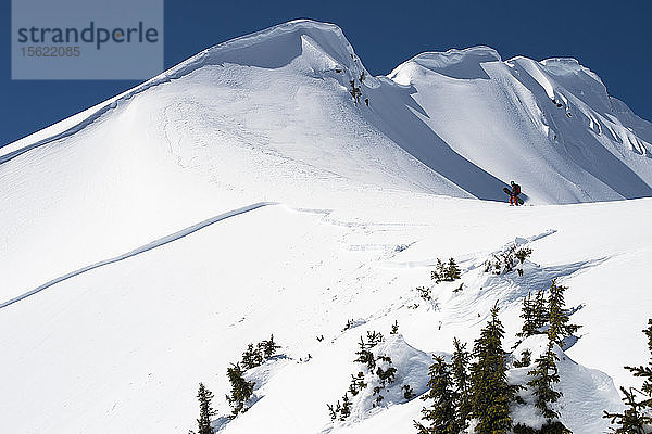 Snowboarder beim Wandern auf einem Bergkamm in der Nähe eines Lawinenabgangs in Kanada
