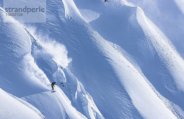 Der Profi-Snowboarder Robin Van Gyn fährt an einem sonnigen Tag mit dem Snowboard in Haines  Alaska  durch frischen Pulverschnee.