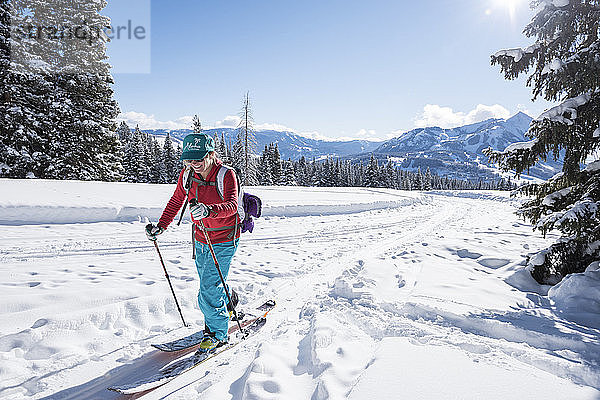 Eine Skifahrerin mit einem Aloha-Hut macht sich von einer alten Straße aus auf den Weg zur Piste  den Mt Crested Butte im Rücken.