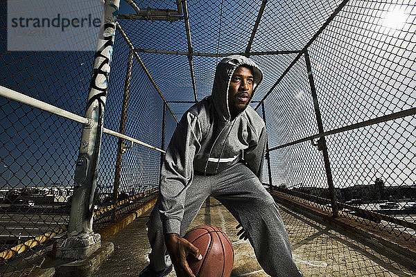 Ein junger Mann spielt auf einer Fußgängerbrücke in San Diego  Kalifornien  mit einem Basketball herum.