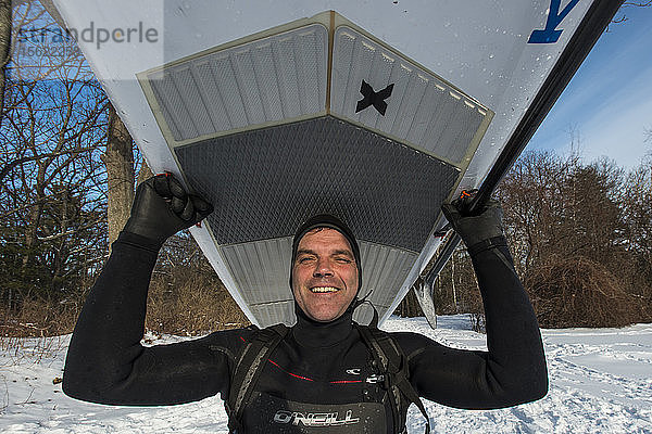 Porträt eines lächelnden Paddelboarders  der ein Paddleboard vor der Küste von Maine trägt