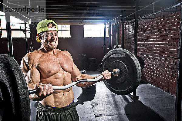 Ein Crossfit-Sportler macht Bizepscurls in einem alten  düsteren Fitnessstudio in San Diego  Kalifornien.