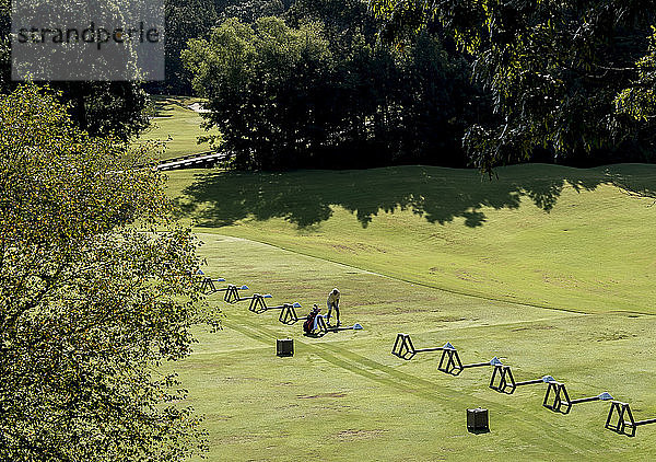 Einzelner Golfer auf der Driving Range eines Golfplatzes
