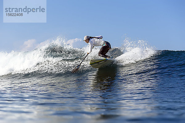 Volle Länge Schuss von einzelnen weiblichen Paddel Surfer Reiten Welle