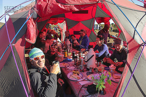 Ein Führer genießt einen Kaffee beim Frühstück in einem Zelt in einem Camp am Kilimandscharo