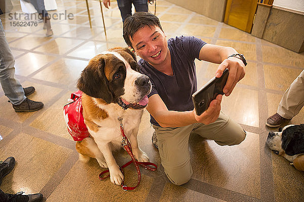 Ein asiatischer Tourist macht ein Selfie mit einem Bernhardinerhund im Grand Hotel Zermatterhof in Zermatt.