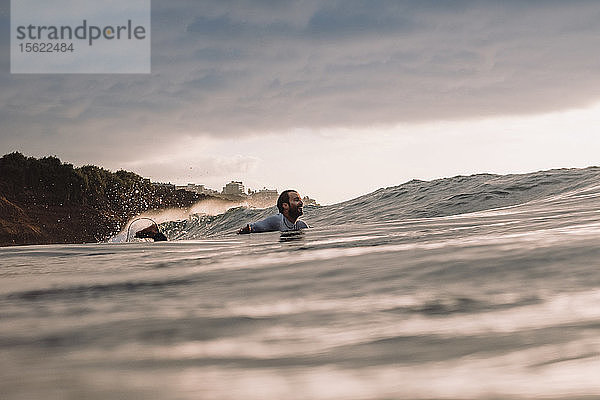 Profi-Surfer Jonathan Gonzalez paddelt zurück zum Gipfel  während die Sonne untergeht  Teneriffa  Kanarische Inseln  Spanien