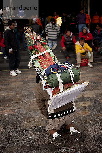 Ein Pilger trägt ein Bild der Jungfrau von Guadalupe während der jährlichen Wallfahrt zur Basilika Unserer Lieben Frau von Guadalupe auf dem Tepeyac-Hügel in Mexiko-Stadt  Mexiko. Guadalupe ist bei den Eingeborenen als Tonantzin bekannt  was in der mexikanischen Sprache Nahuatl Unsere Mutter bedeutet. Jedes Jahr kommen Millionen von Menschen zu dieser Wallfahrt.