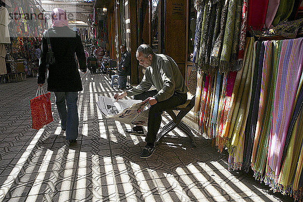 Ein Händler liest die Zeitung im Medina-Viertel von Marrakesch