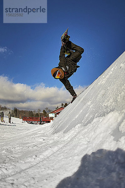 Ein Snowboarder macht einen Handplant auf einem Feature im Terrain Park.