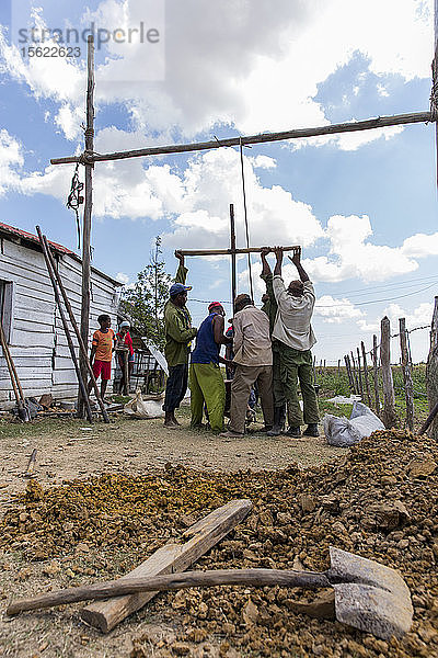 Eine Gruppe von Männern gräbt einen Brunnen vor einem Dorfhaus  Kuba
