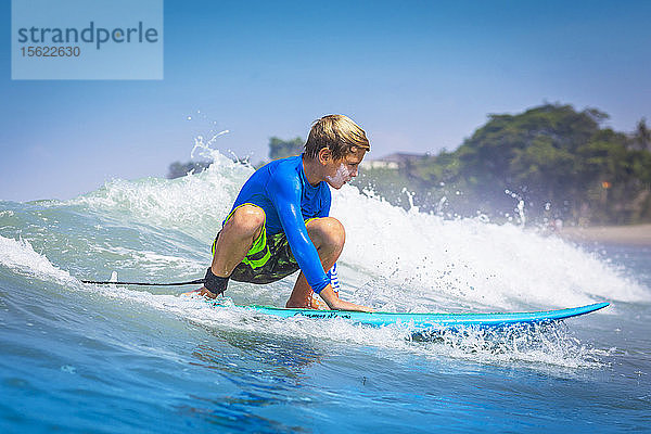 Junger Surfer  glücklicher Junge im Ozean auf dem Surfbrett