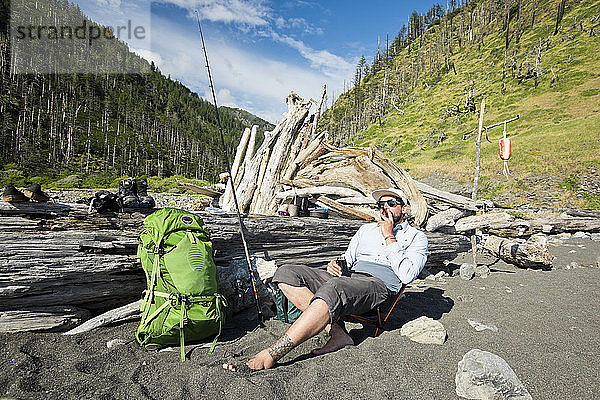 Ein Mann entspannt sich mit Flachmann und Zigarre auf seinem Zeltplatz an der Lost Coast
