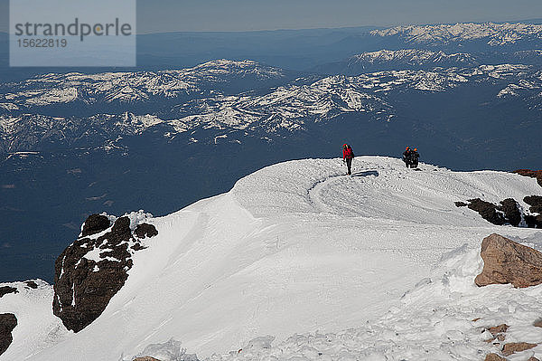 Jungen im Alter von 13 bis 17 Jahren von der Venturing Crew 191 aus Glendora  Kalifornien  setzen ein Jahr Training in die Praxis um  als sie versuchen  den Gipfel des Mount Shasta über die Avalanche Gulch-Route im Shasta Trinity National Forest in Nordkalifornien zu erreichen. Der Mount Shasta ist ein massiver  vergletscherter Vulkan und mit 14.179 Fuß der zweithöchste Gipfel in der Cascade Range und der fünfthöchste in Kalifornien; er ist mit keinem anderen Gipfel verbunden und erhebt sich abrupt 10.000 Fuß über das umliegende Gelände. Die Pfadfinder der Venturing Crew 191 (Venturing Crews sind ein Zweig der Pfadfinder  der sich auf abenteuerliche Aktivitäten konzentriert) hatten sich ein Jahr lang auf die Besteigung des Mount Shasta vorbereitet. Dies war ihre erste Erfahrung mit dem Klettern in steilem Schnee  und sie wurden bei der Besteigung von Führern der SWS Mountain Guides unterstützt. Mark Howlett  Dillon Travis und ihr Führer Casey Hurden kommen auf dem Gipfel des Misery Hill an  der sich auf einer Höhe von etwa 13.900 Fuß und in der Nähe des Gipfelblocks des Mount Shasta befindet; darunter erstrecken sich die umliegenden Gipfel und Täler  Shasta Trinity National Forest  Kalifornien.
