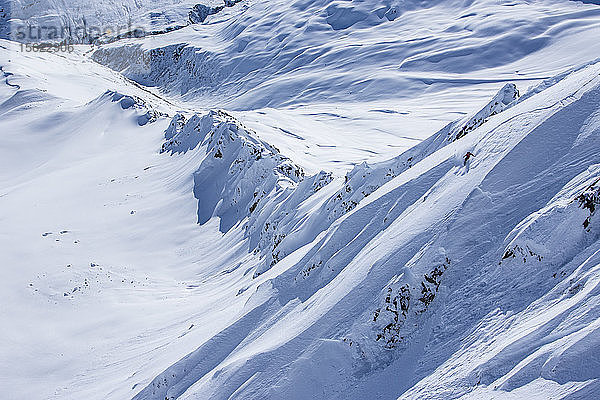 Die professionelle Snowboarderin Helen Schettini fährt an einem sonnigen Tag beim Snowboarden in Haines  Alaska  durch frischen Pulverschnee.