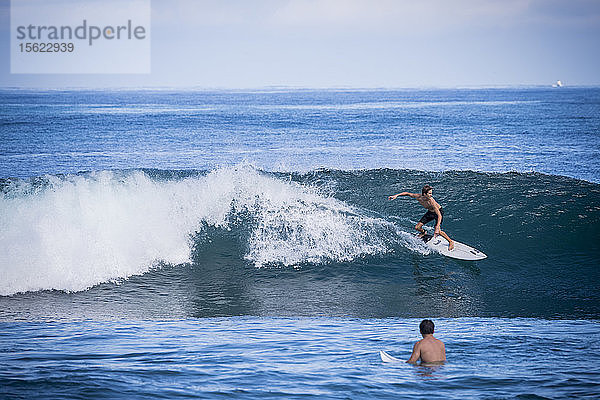 Totale Aufnahme eines jungen Mannes beim Surfen im Meer
