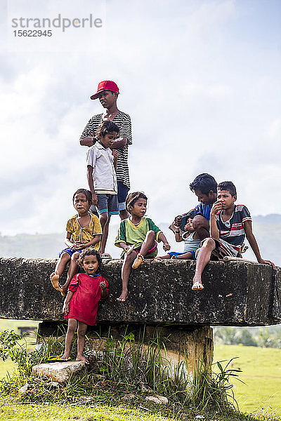 Gruppe von Kindern  die auf einer Steinplattform sitzen und stehen  Sumba  Indonesien
