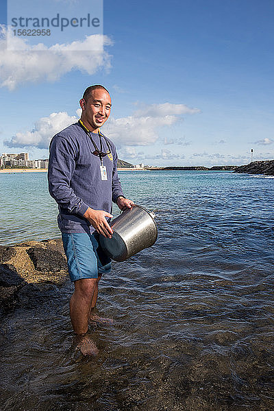 Wataru Kumagai von der Abteilung für sauberes Wasser des Gesundheitsministeriums des Bundesstaates Hawaii demonstriert am Ala Moana Beach in Honolulu die Entnahme von Wasserproben an hawaiianischen Stränden mit Instrumenten wie einem Trübungsmessgerät. Um den vollen Umfang der Messwerte zu erhalten  müssen die Laborarbeiten außerhalb des Landes durchgeführt werden.