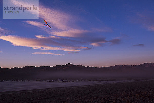 Flugzeug fliegt über Bergkette in Nevada Wüste gegen den Himmel in der Abenddämmerung