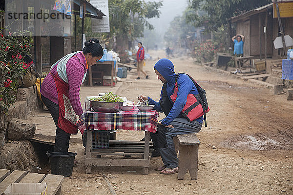 Robert Hahn isst Nudelsuppe zum Frühstück in der Hauptstraße von Muang Ngoi  Laos.