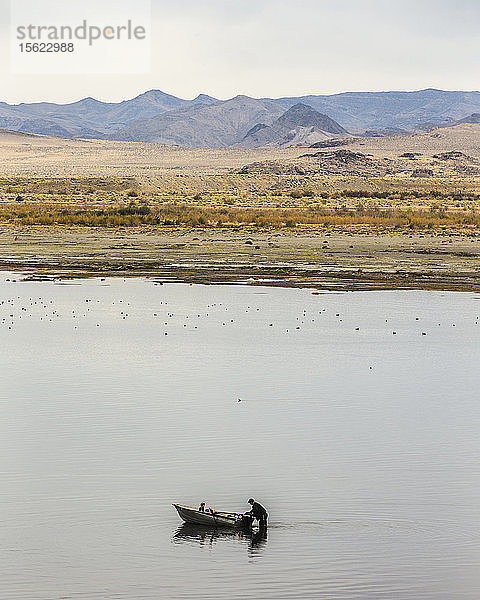 Mann und junges Mädchen lassen ein kleines Boot im Pyramid Lake zu Wasser