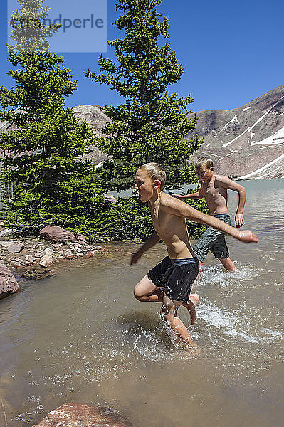 Die Jungen rennen ans Ufer  nachdem sie in das eiskalte Wasser des Milk Lake gesprungen sind  der von schneebedeckten Gipfeln umgeben ist. Dies geschah während einer Pause am fünften Tag der sechstägigen Rucksacktour von Troop 693 durch das High Uintas Wilderness Area  Uintas Range  Utah.