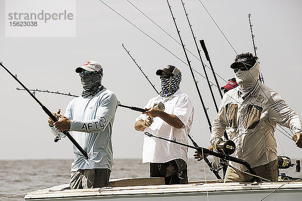 Eine Gruppe von Fischern holt ihre Leinen ein.