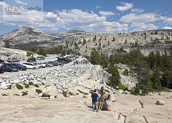 Ein riesiger  fast kahler Granitfelsen  bekannt als Olmsted Point  bietet den Besuchern des Yosemite-Nationalparks die Möglichkeit  die herrliche Landschaft der Sierra zu erkunden und zu genießen  die man von der Tioga Road aus sehen kann. Die Spitze des berühmten Half Dome ist in der Mitte rechts zu sehen.