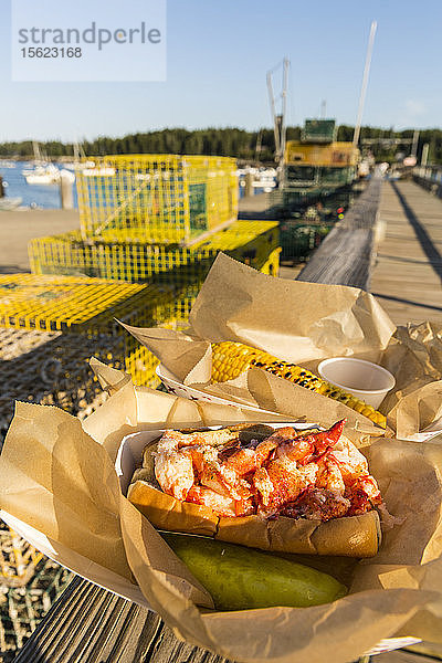 Ein Hummerbrötchen und Mais auf dem Dock hinter dem Restaurant Miller's Wharf  Tenants Harbor  Maine