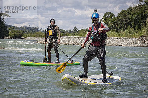 Foto von zwei Männern  die für ein Foto posieren  während sie auf Stand-up-Paddleboards paddeln  peruanischer Amazonas  Manu-Nationalpark  Peru