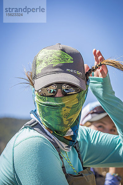 Eine Frau spielt mit ihren Haaren  während sie im Gallatin River in Montana angelt.