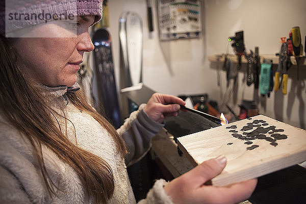 Seitenansicht einer Frau mit Strickmütze beim Wachsen von Skiern in einer Garage  Missoula  Montana  USA