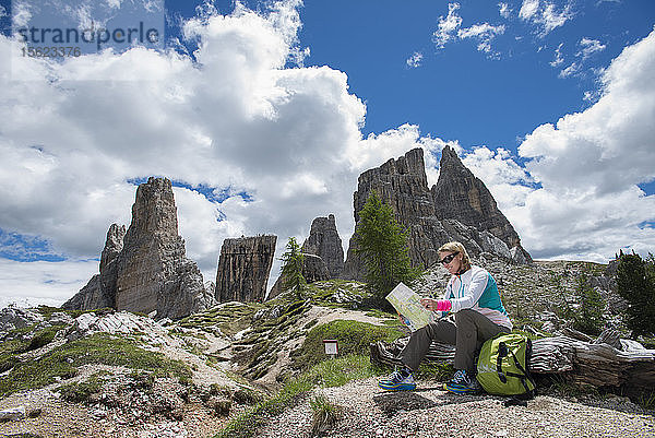 Eine Frau liest eine Karte im Gebiet der Cinque Torri in den Dolomiten  Italien
