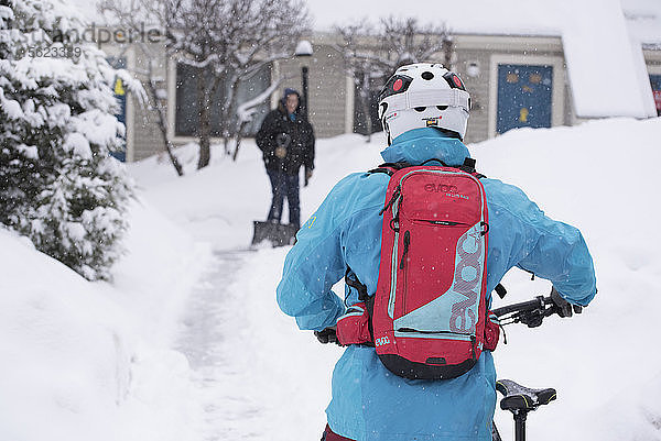 Im Winter ein Fahrrad mit dicken Reifen durch die Nachbarschaft schieben.