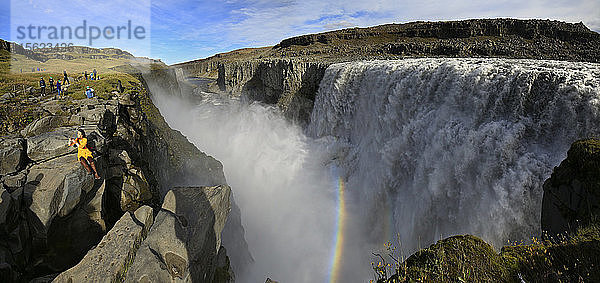 Dettifoss-Wasserfall mit einem Touristen  der auf einem Felsen sitzt und ein Selfie macht  Island.