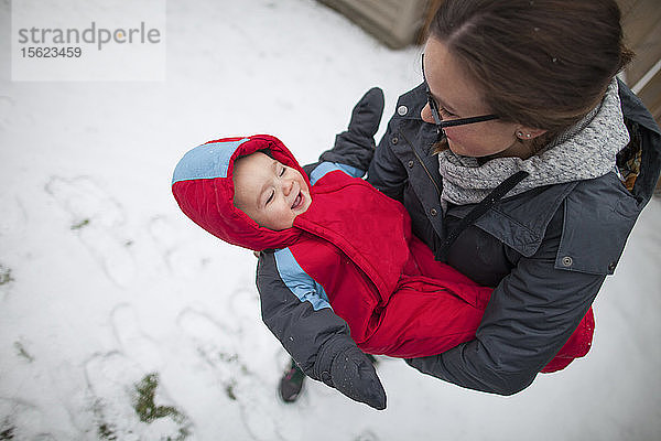 Mutter hält lachendes Baby im Winter im Freien  während sie warme Kleidung trägt  Langley  British Columbia  Kanada