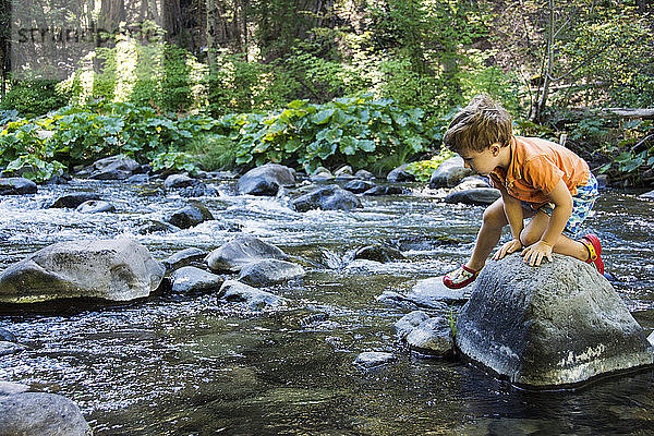 Ein kleiner Junge navigiert über Felsen in Deer Creek  Kalifornien.