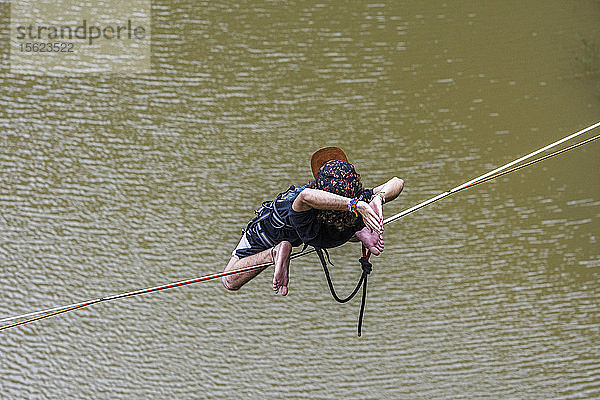 Abenteuerlustiger Mann in ungewöhnlicher Position auf der Slackline  Steinbruch Dibs  Maripora  Bundesstaat Sao Paulo  Brasilien