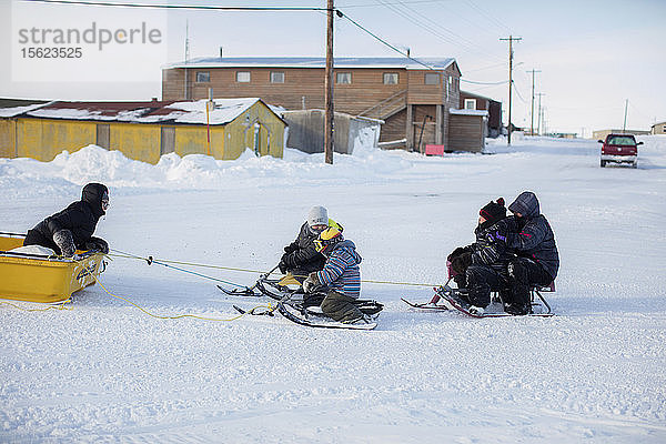 Kinder werden von einem Schneemobil durch die Straßen von Tuktoyaktuk  Northwest Territories  Kanada  gezogen  13. März 2016.