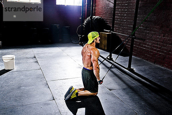 Ein Crossfit-Sportler trainiert mit Widerstandsbändern in einem alten  düsteren Fitnessstudio in San Diego  Kalifornien.