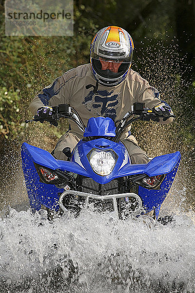 Mann fährt Quad im Fluss Alberche