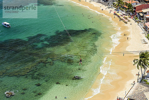 Foto einer abenteuerlustigen Person auf einer Seilrutsche über einem tropischen Strand  Morro de Sao Paulo  Süd-Bahia  Brasilien