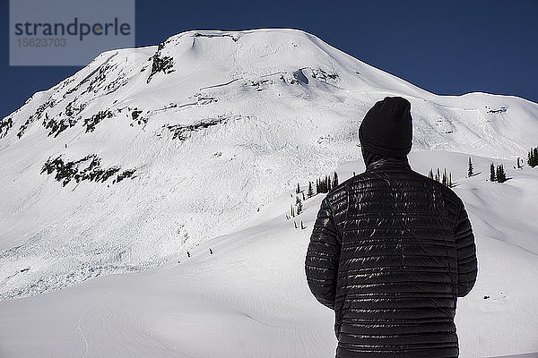 Mann schaut auf eine kürzlich abgegangene Lawine im Backcountry