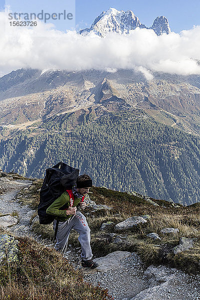 Mann beim Wandern in den Bergen mit Paddelbrett auf dem Rücken  Chamonix-Mont-Blanc  Haute-Savoie  Frankreich