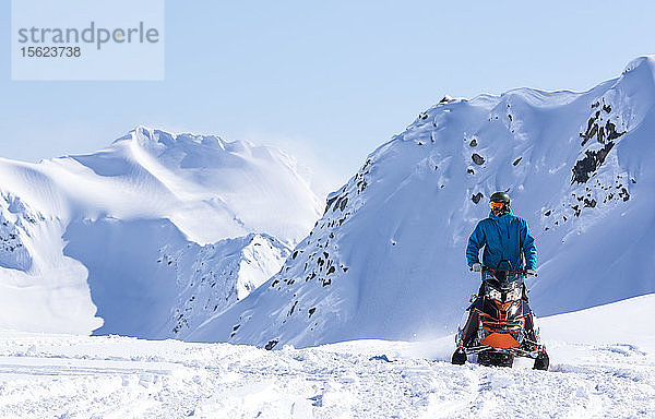 Snowboarder mit Schneemobil für den Zugang fährt in Richtung der Kamera auf einem sonnigen Wintertag